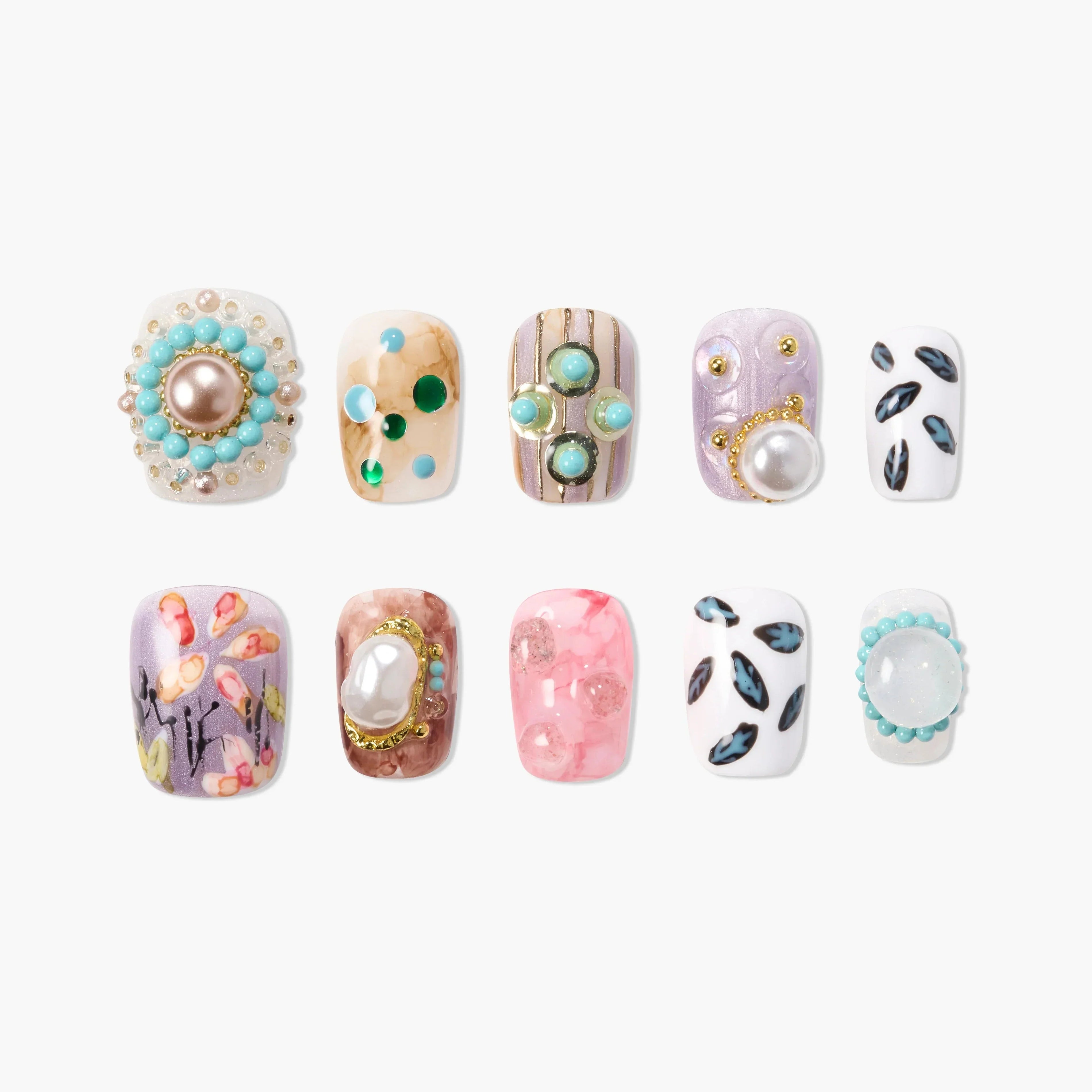Handmade press-on nails with colorful, jeweled, and floral art designs on a white background.