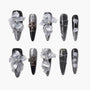 Black and silver press-on nails with 3D clear floral accents and metallic cross charms