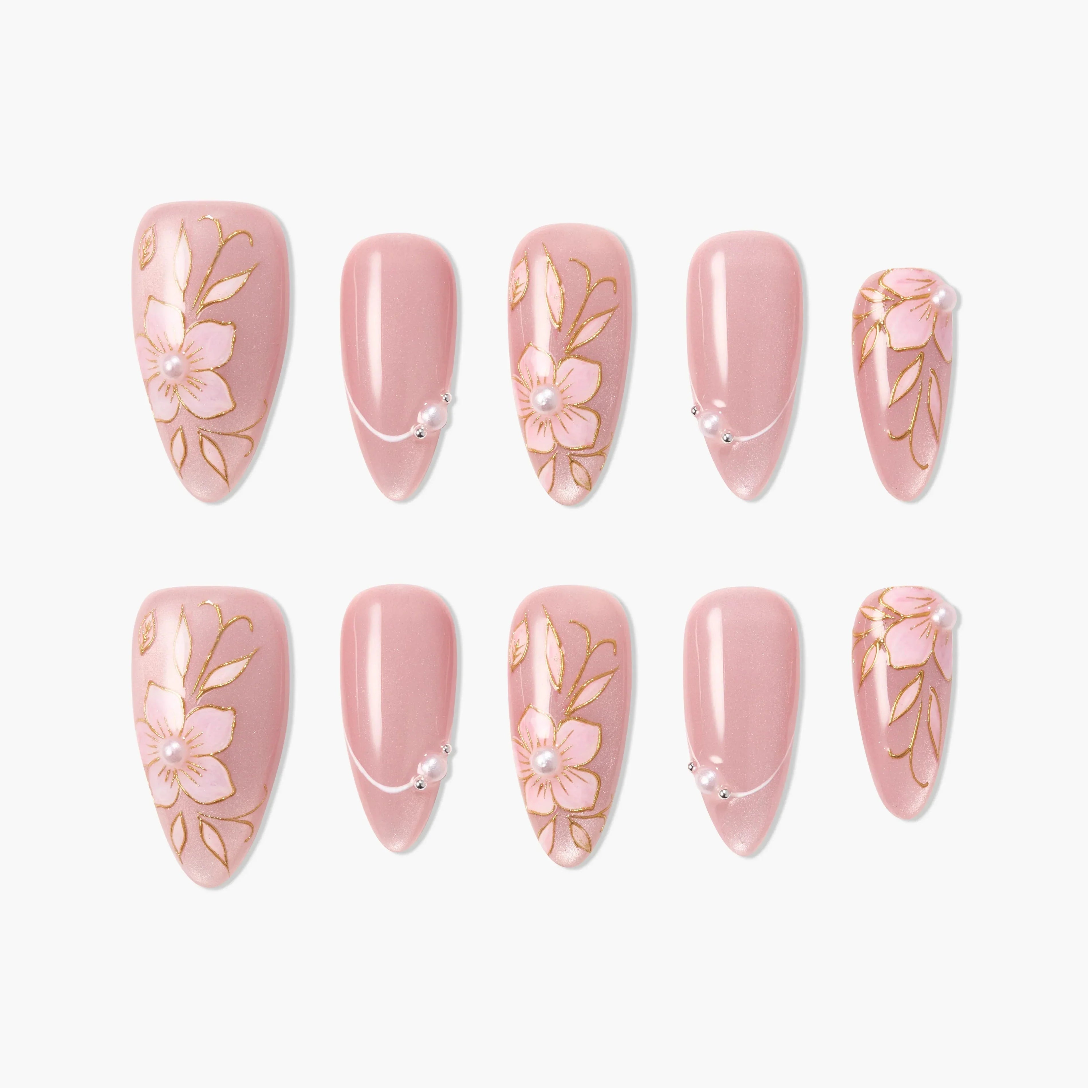 Pink press-on nails with floral designs, gold accents, and pearl embellishments.