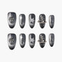 Black glitter press-on nails with silver cross, star, and planet charms, elegant nail art