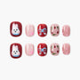 Handmade press-on nails with red, pink, and glitter finishes, featuring dog, paw print, bow, cherry, and polka dot designs.