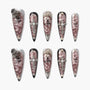 Long coffin-shaped press-on nails with metallic pink finish, jeweled cross, gothic details, and silver accents