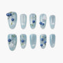 Handmade press-on nails with blue shimmer, botanical designs, and 3D blue berries on a white background