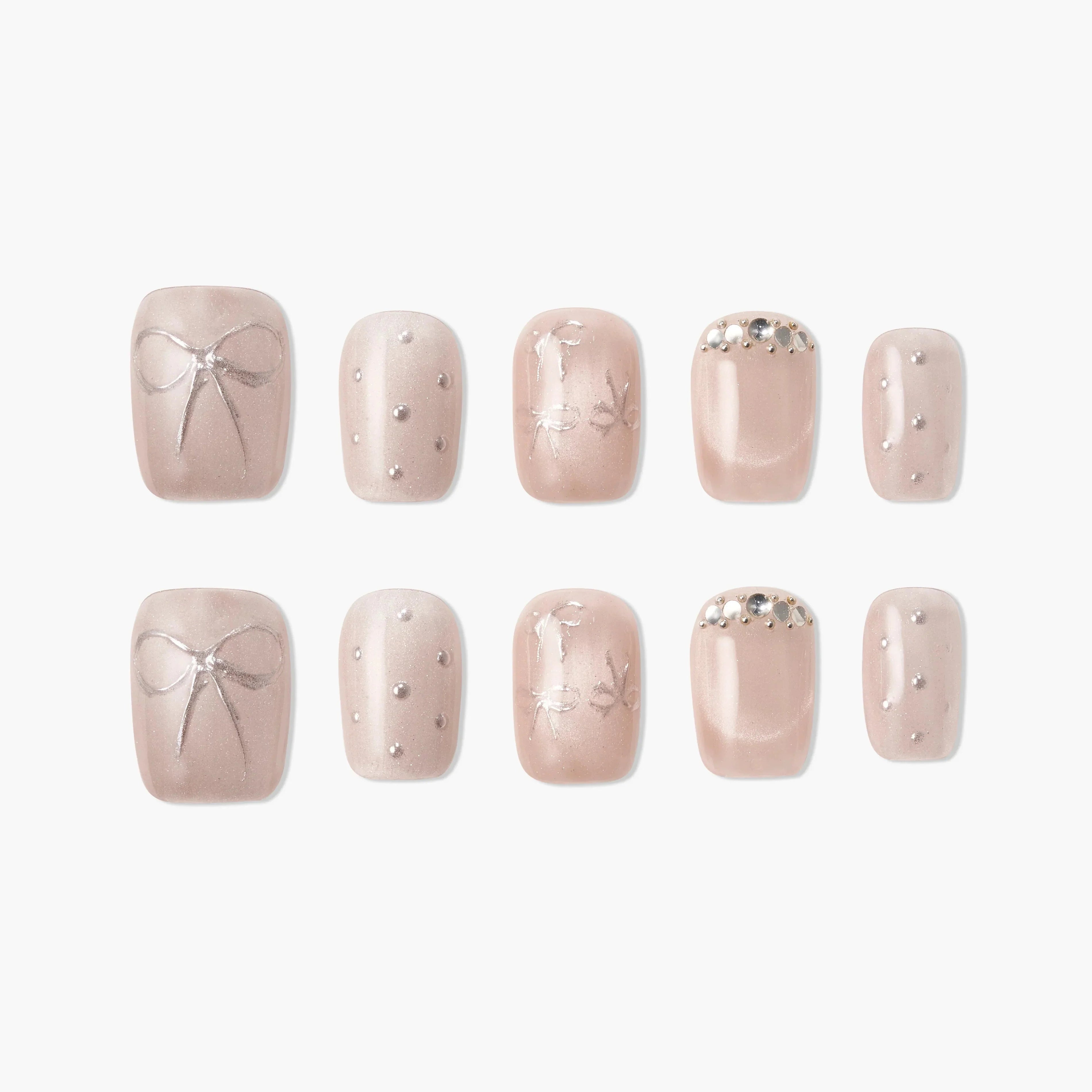 Handmade nude press-on nails with silver bow, pearl accents, and rhinestone details