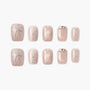 Handmade nude press-on nails with silver bow, pearl accents, and rhinestone details
