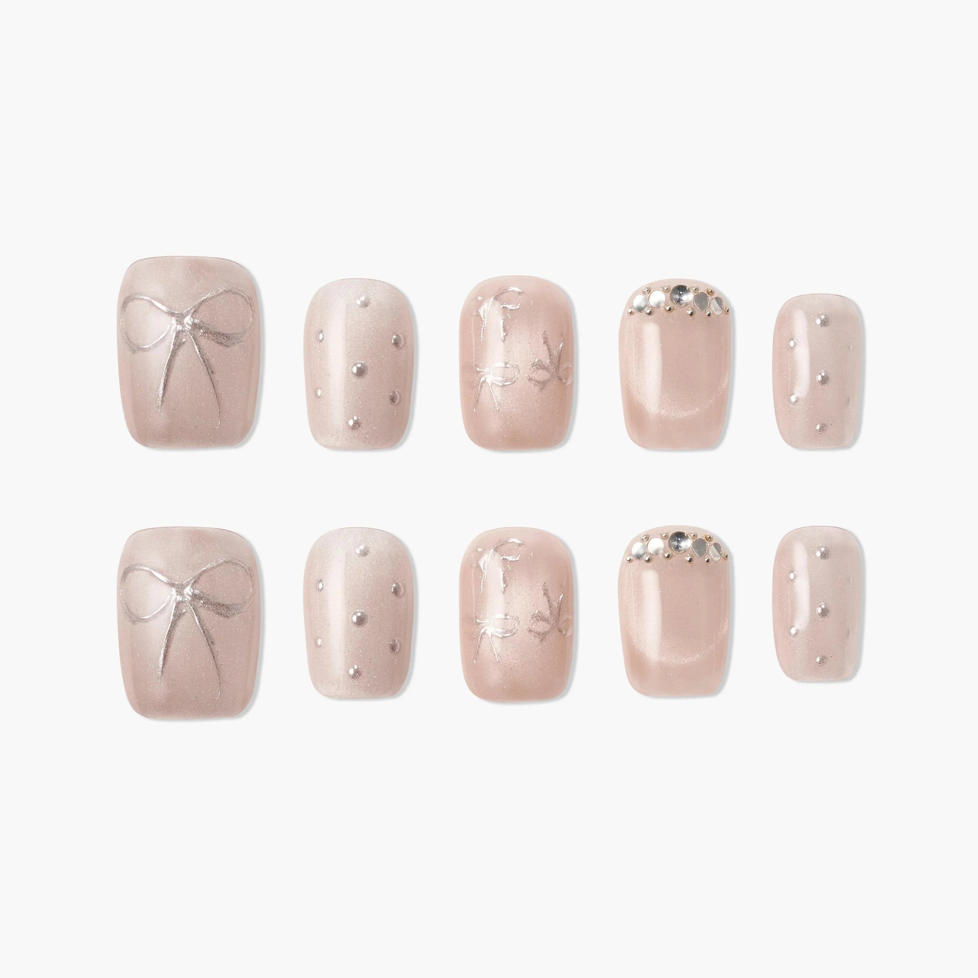 Handmade nude press-on nails with silver bow, pearl accents, and rhinestone details