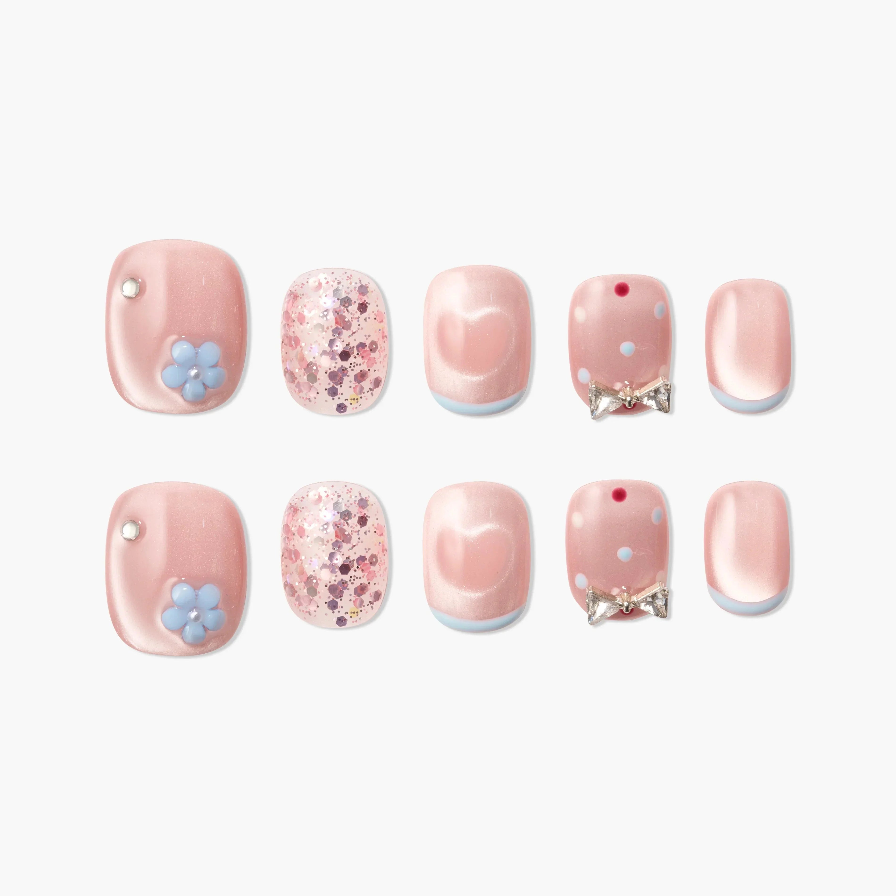 Pink press-on nails with floral accents, bows, glitter, and heart designs, displayed on white background.