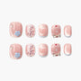 Pink press-on nails with floral accents, bows, glitter, and heart designs, displayed on white background.