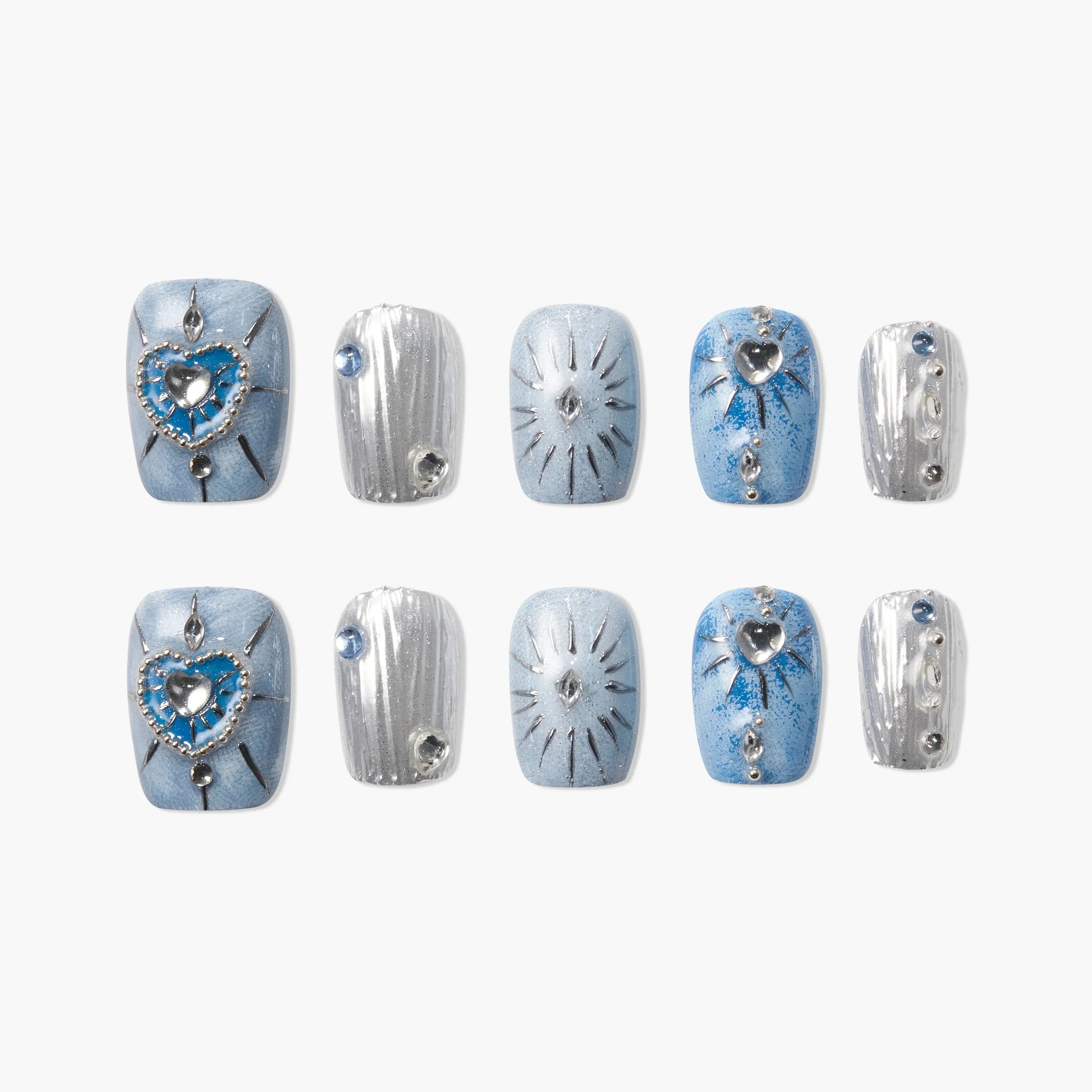 Blue and silver press-on nails with heart, gem, and starburst designs, arranged on white.