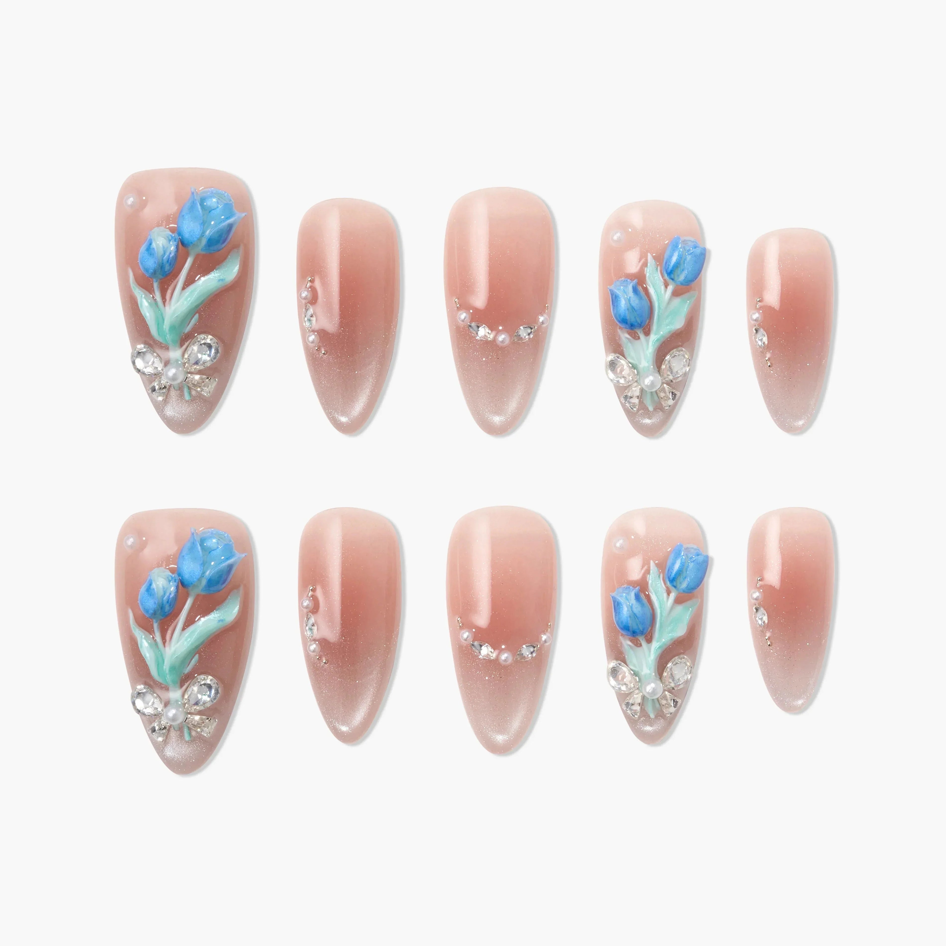 Nude almond press-on nails with blue floral 3D accents and rhinestone details