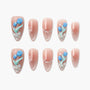 Nude almond press-on nails with blue floral 3D accents and rhinestone details