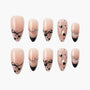 Handmade press-on nails with nude base, black hearts, bows, and rhinestone accents, displayed on white background.