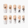 Handmade press-on nails with nude and white marble design, silver 3D star and cross charms, and rhinestone accents.