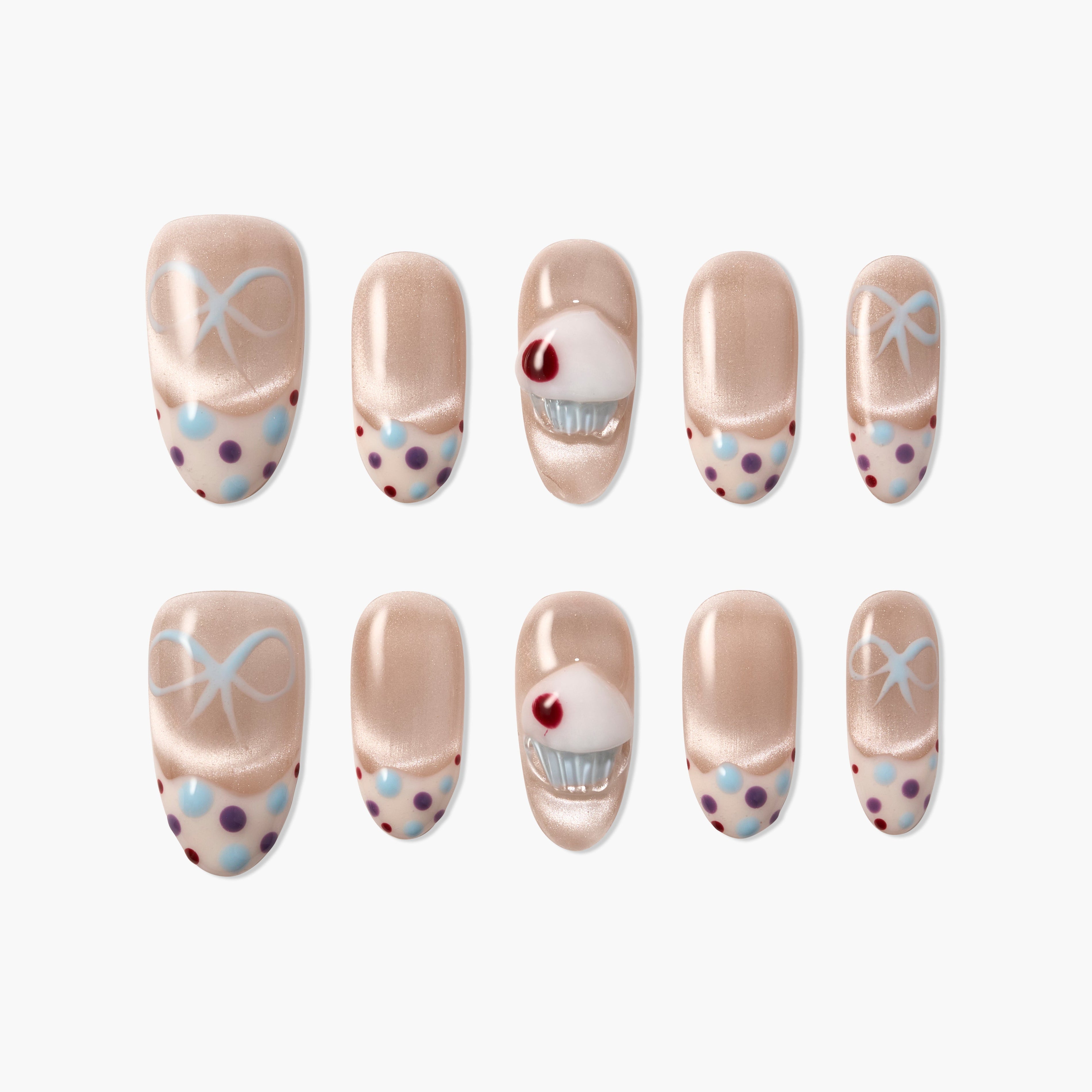 Handmade press-on nails with nude base, polka dots, blue bows, and 3D cupcake accent design