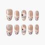 Handmade press-on nails with nude base, polka dots, blue bows, and 3D cupcake accent design