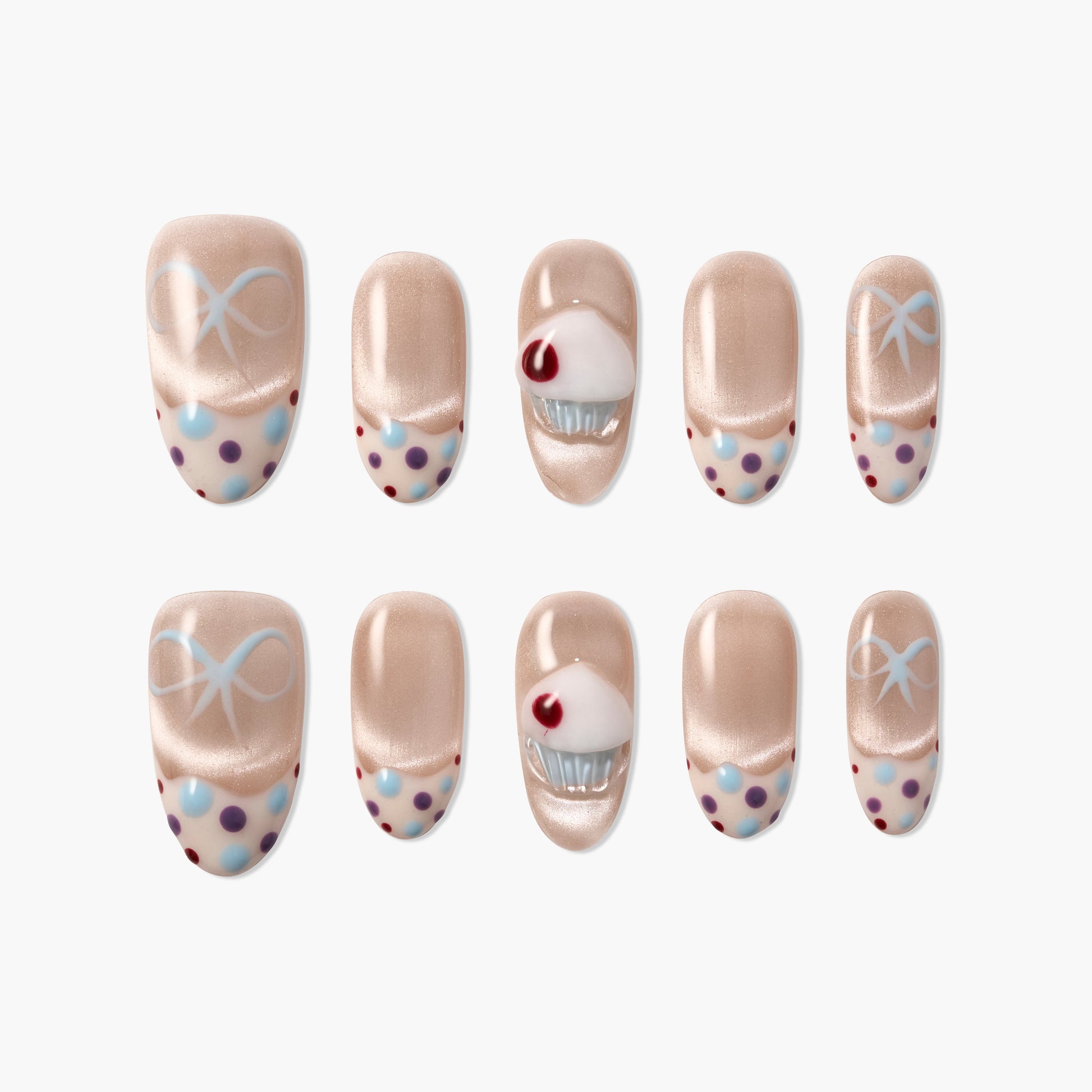Handmade press-on nails with nude base, polka dots, blue bows, and 3D cupcake accent design