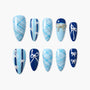 Blue press-on nails with plaid, bow, and pearl accents in various elegant designs