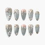 Handmade press-on nails with metallic light blue base, 3D floral designs, rhinestones, and glitter tips.