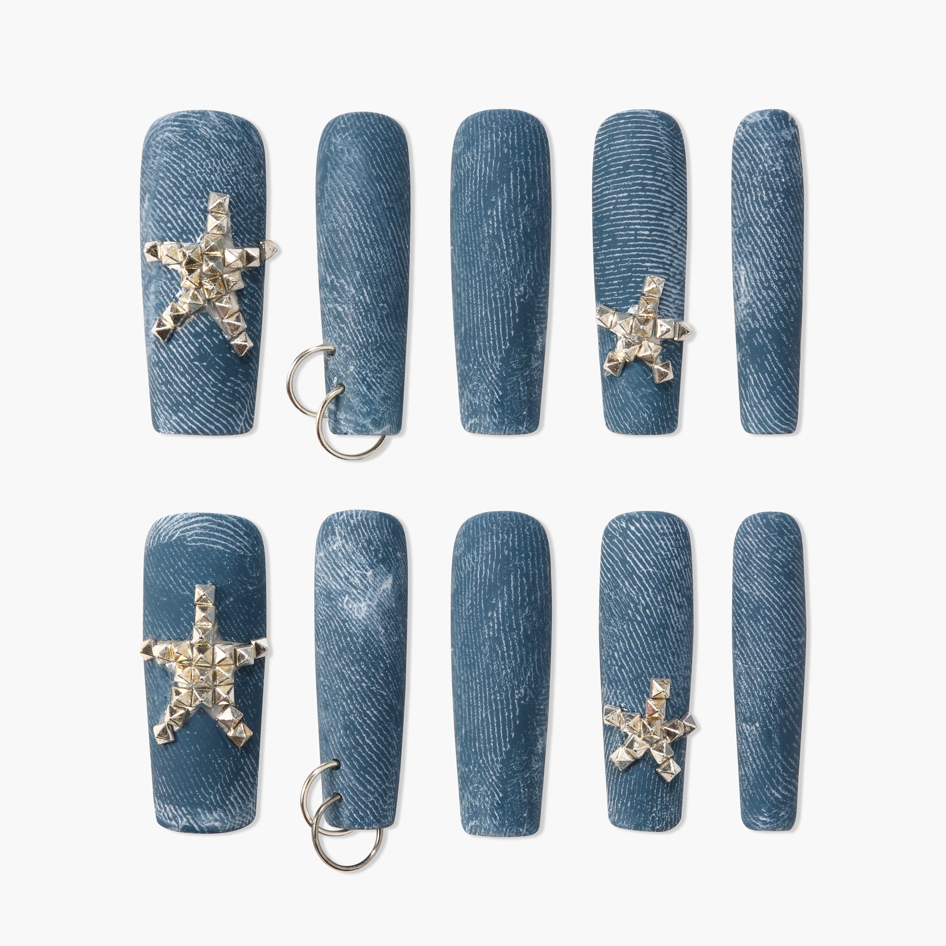 Blue denim press-on nails with silver star studs and metal ring accents, arranged in rows.