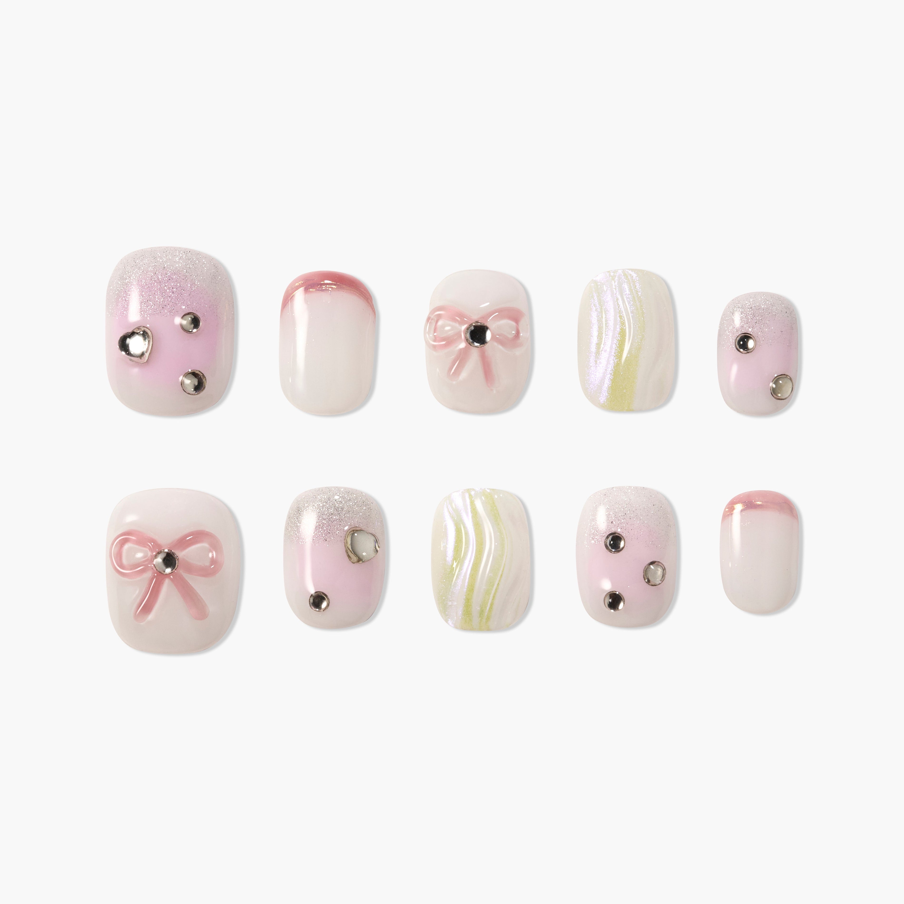 Pink and white press-on nails with bow accents, rhinestones, and swirl designs