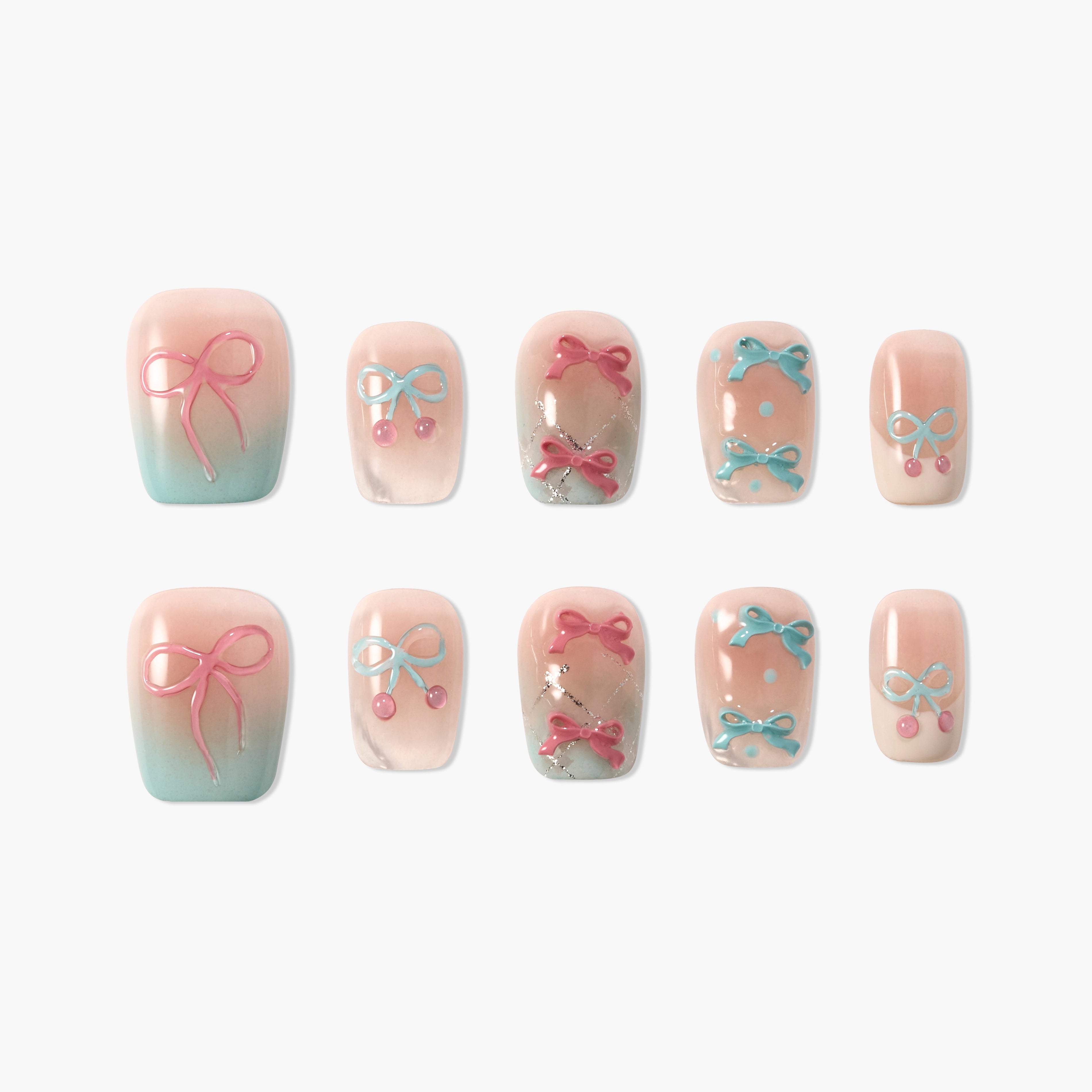 Handmade press-on nails with pink and blue bow designs and pastel gradient tips