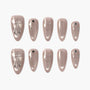 Handmade nude press-on nails with silver bow, heart, and star accents, glossy finish