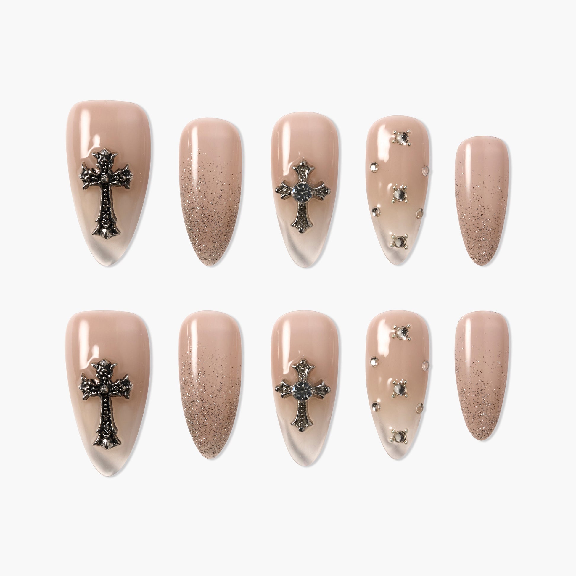 Nude press-on nails with metallic cross charms, rhinestones, and glitter accents, stiletto shape