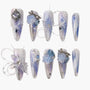 Long ombre blue and white press-on nails with silver glitter, 3D floral accents, and rhinestones