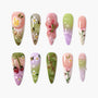 Handmade press-on nails with 3D floral designs, bees, cherries, and pastel colors