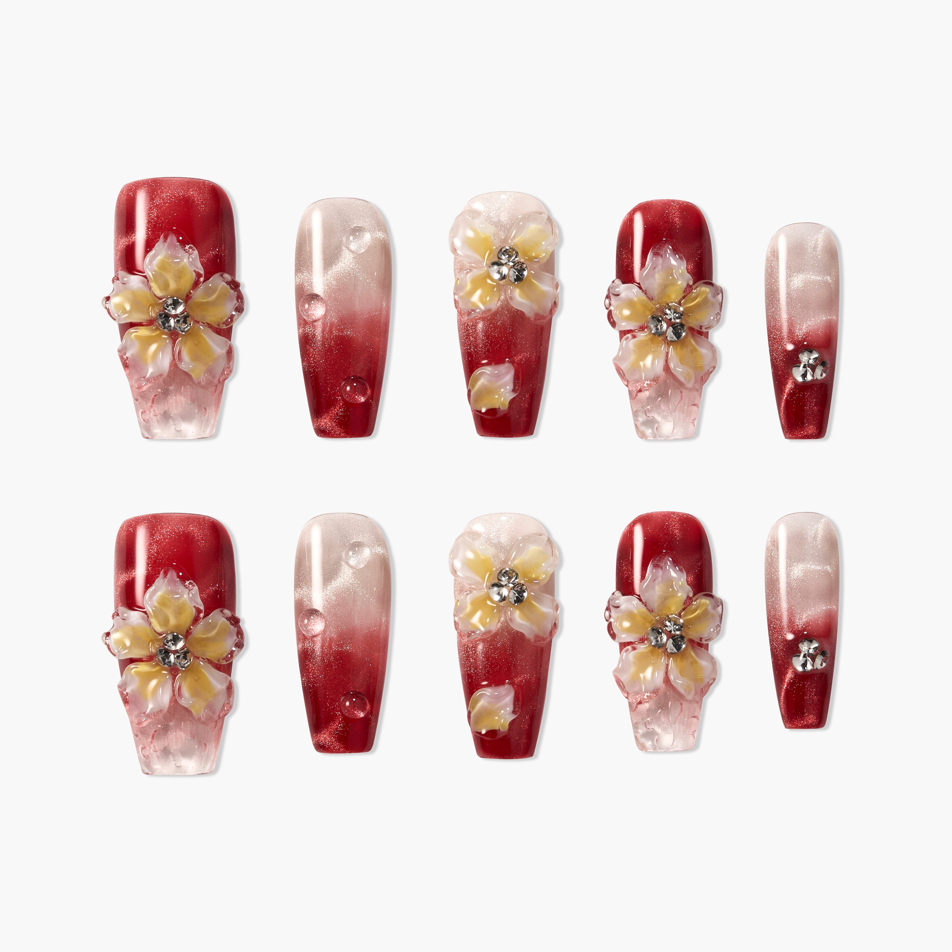 Red and pink ombre press-on nails with 3D floral accents and rhinestones, arranged on a white background.
