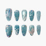 Blue press-on nails with pearl accents, glitter, and 3D ocean-inspired designs