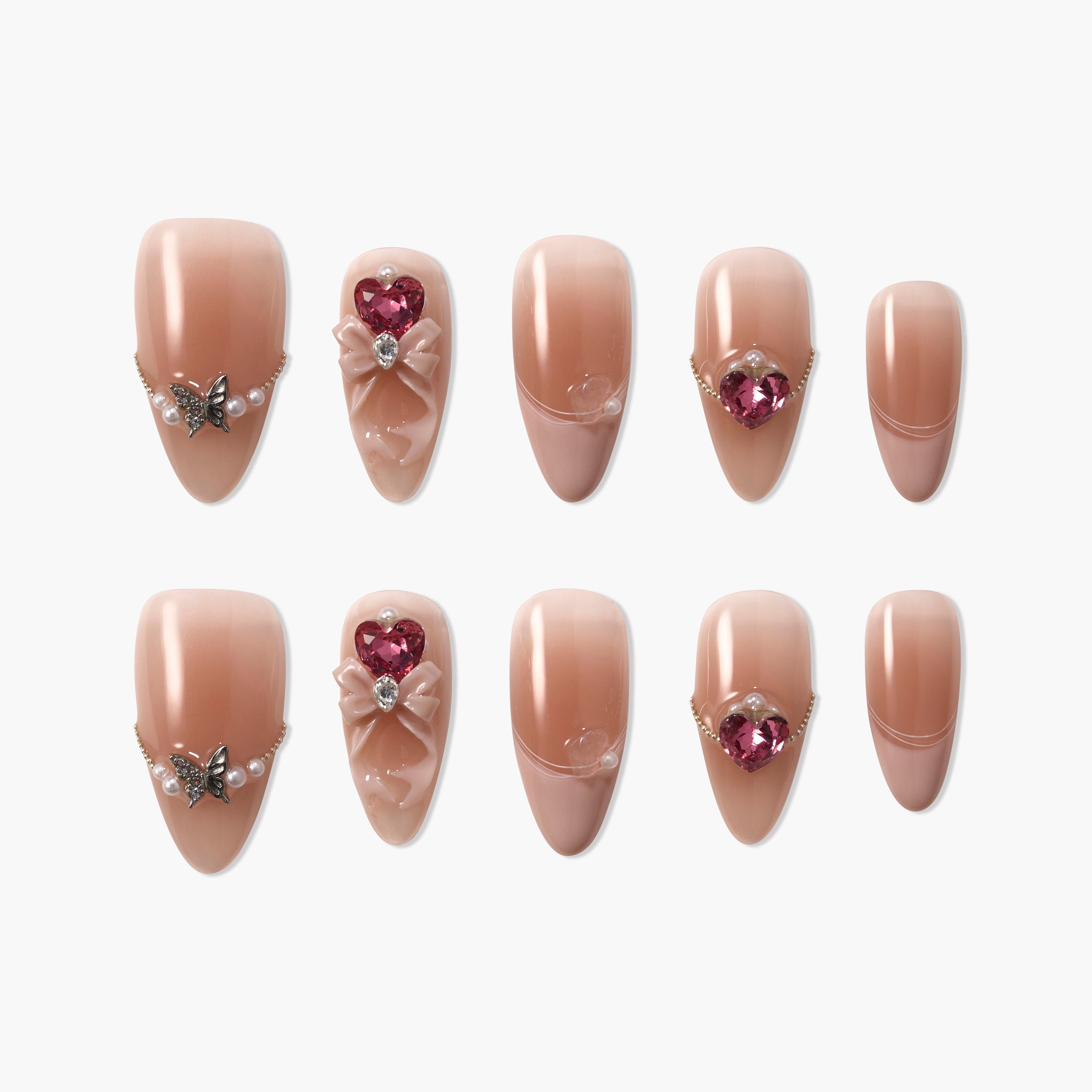 Handmade nude press-on nails with pearl, butterfly, bow, and heart gem embellishments.