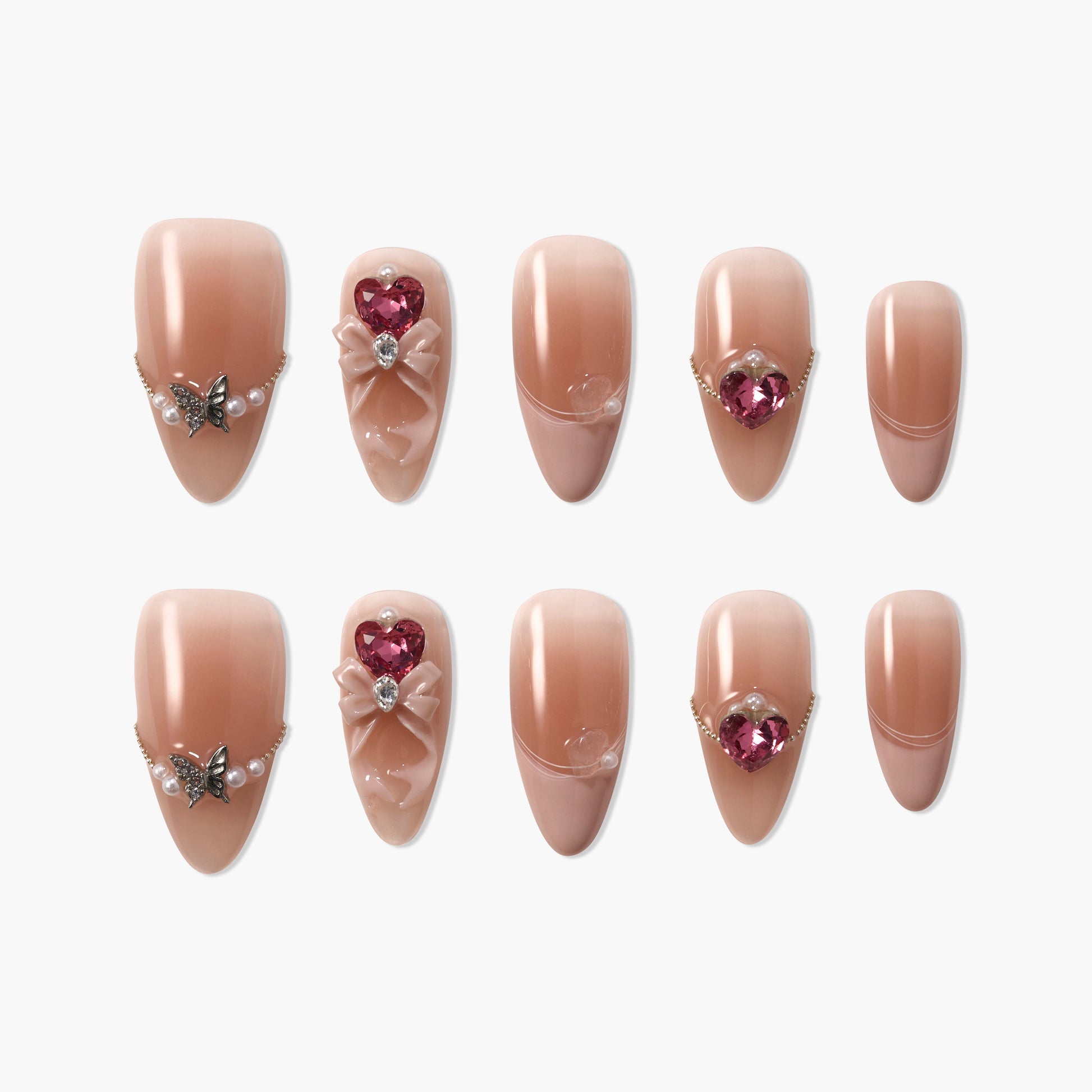 Handmade nude press-on nails with pearl, butterfly, bow, and heart gem embellishments.
