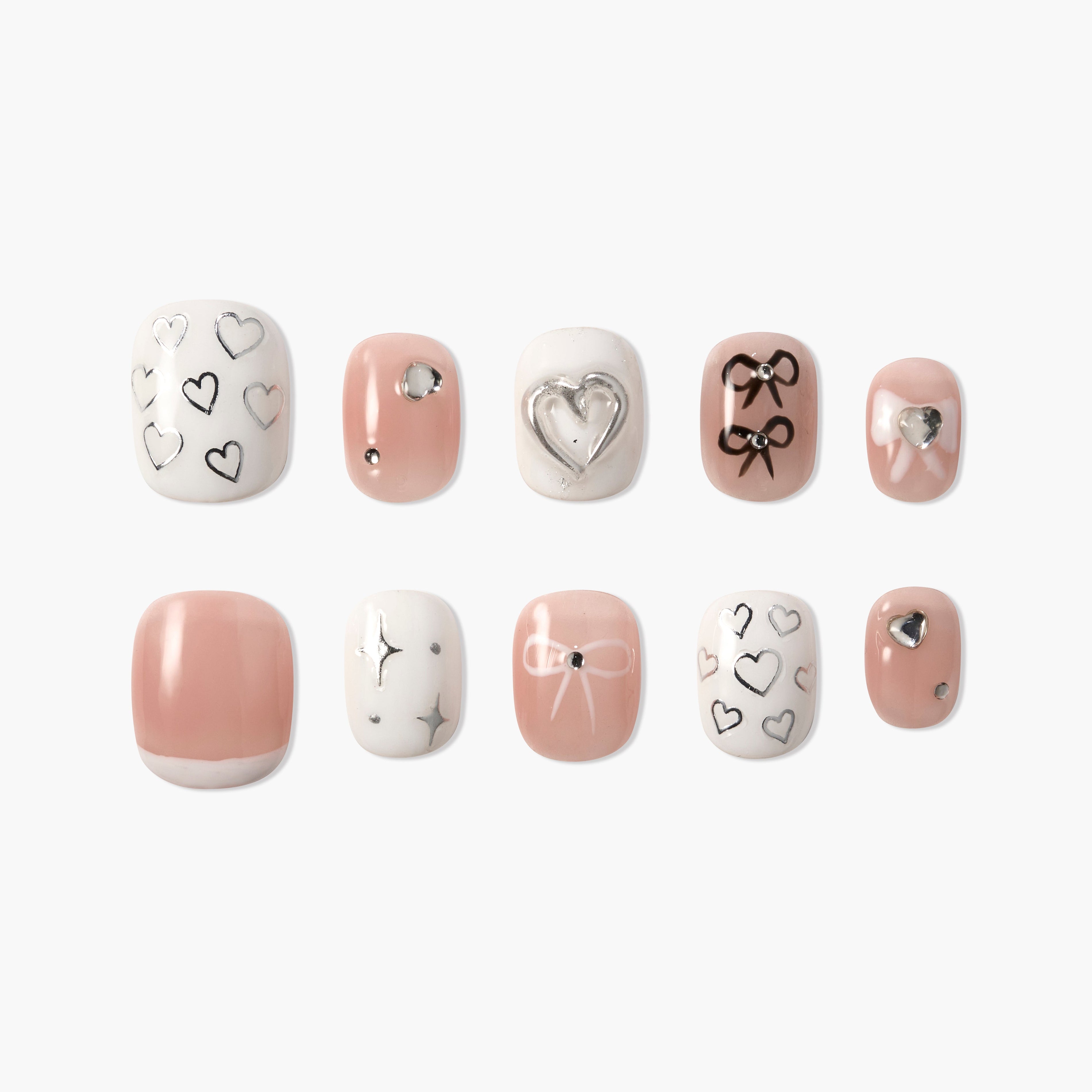Pink and white press-on nails with heart, bow, and gem designs on white background