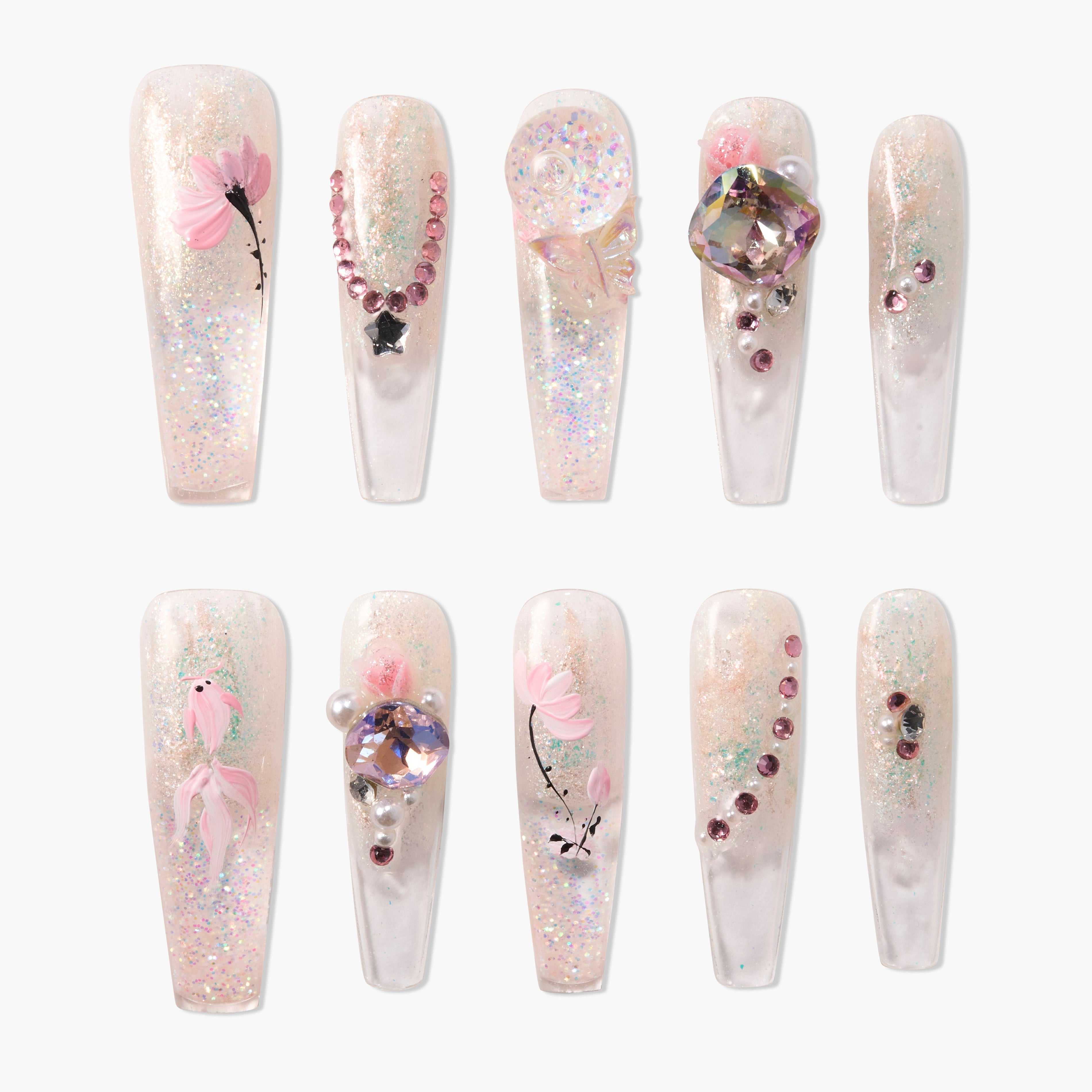 Handmade press-on nails with glitter, pink floral designs, and 3D gemstone accents