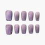 Handmade press-on nails with glittery purple star and swirl designs on mauve background