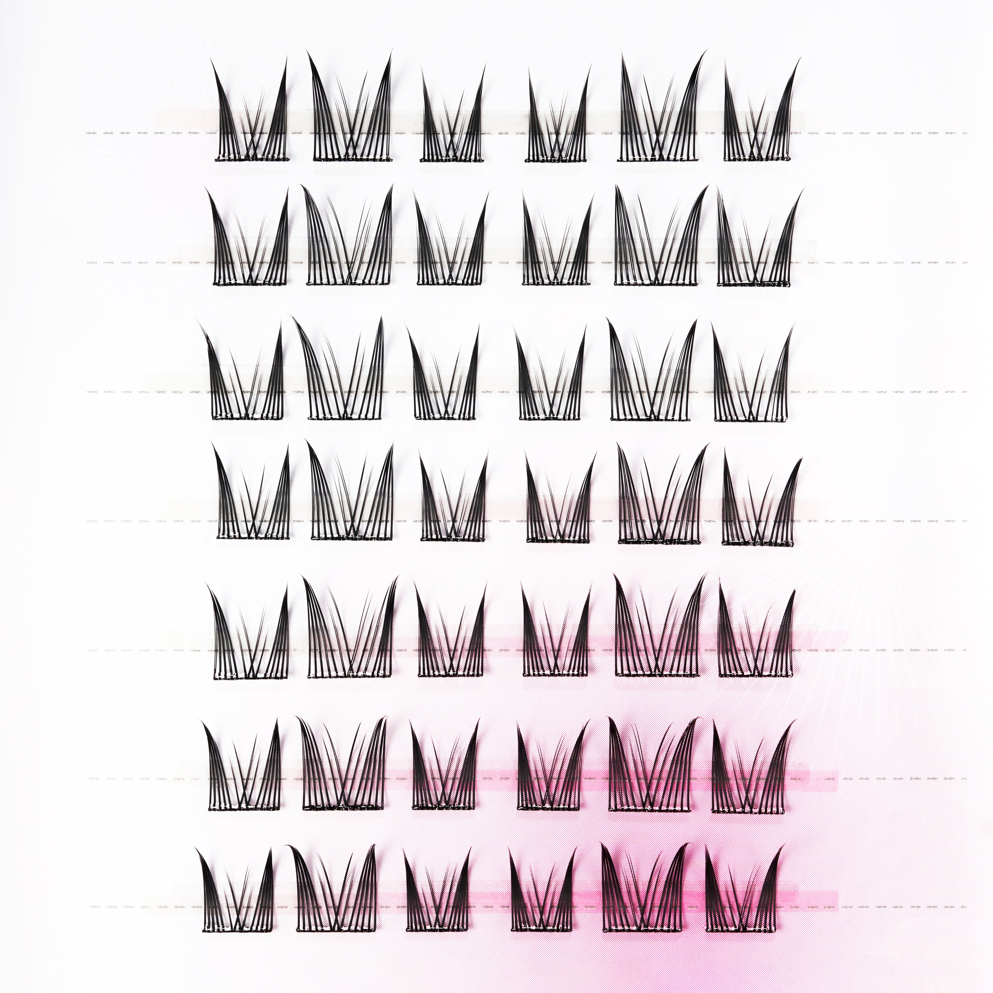 Tray of handmade false eyelash clusters with wispy, crisscross style on white background