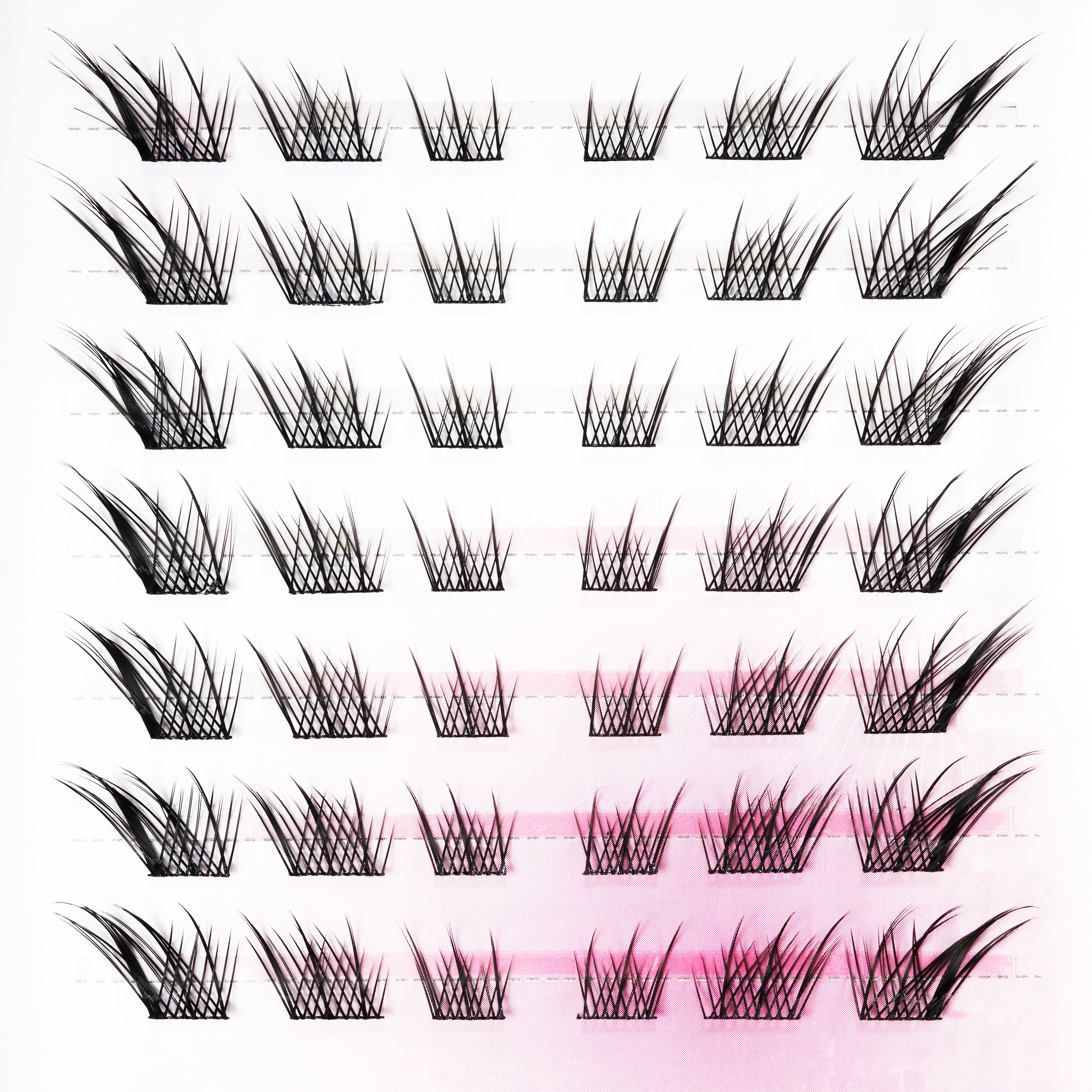 Various styles of handmade wispy false eyelashes arranged in rows on a white background