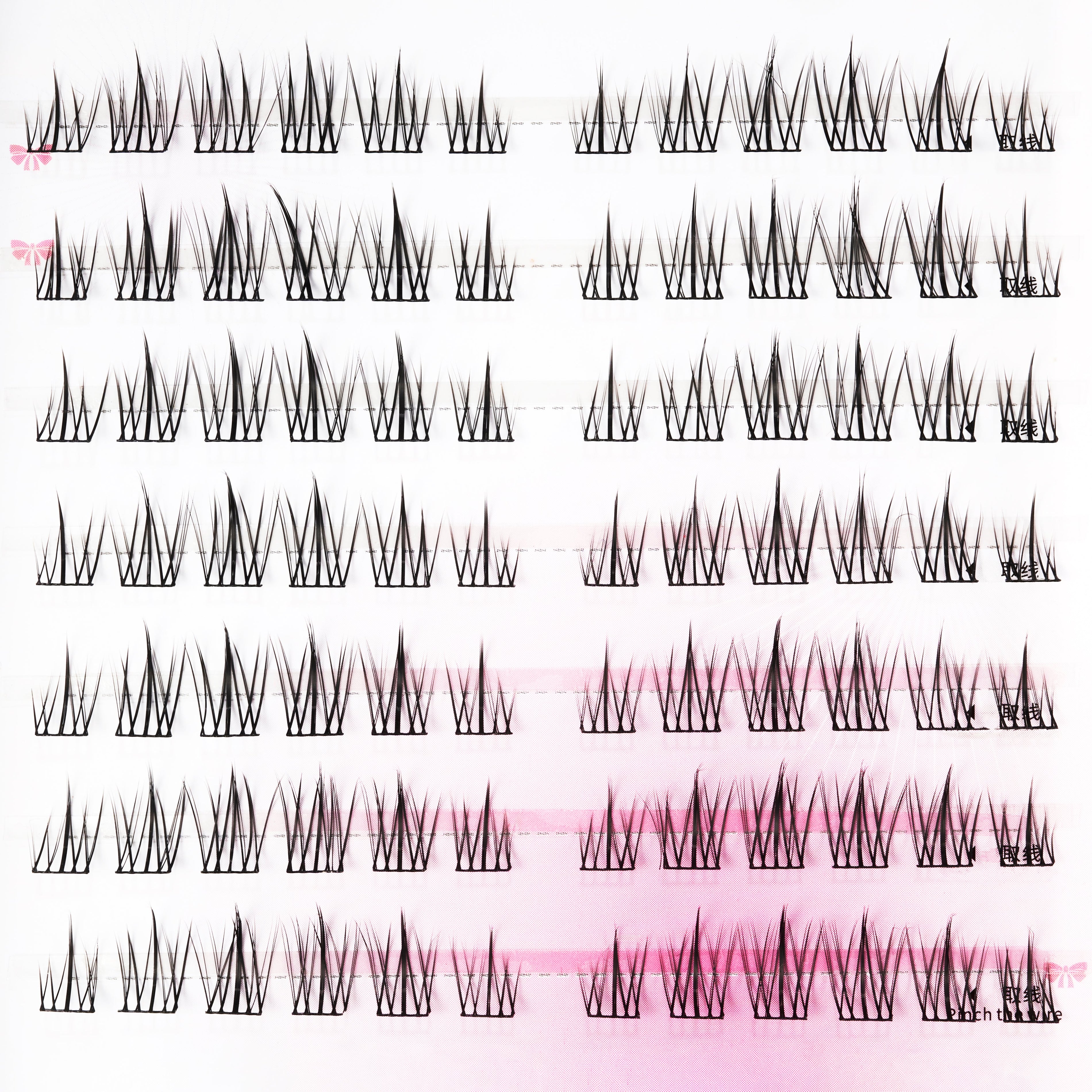 Multiple rows of handmade individual false eyelashes on white and pink background.