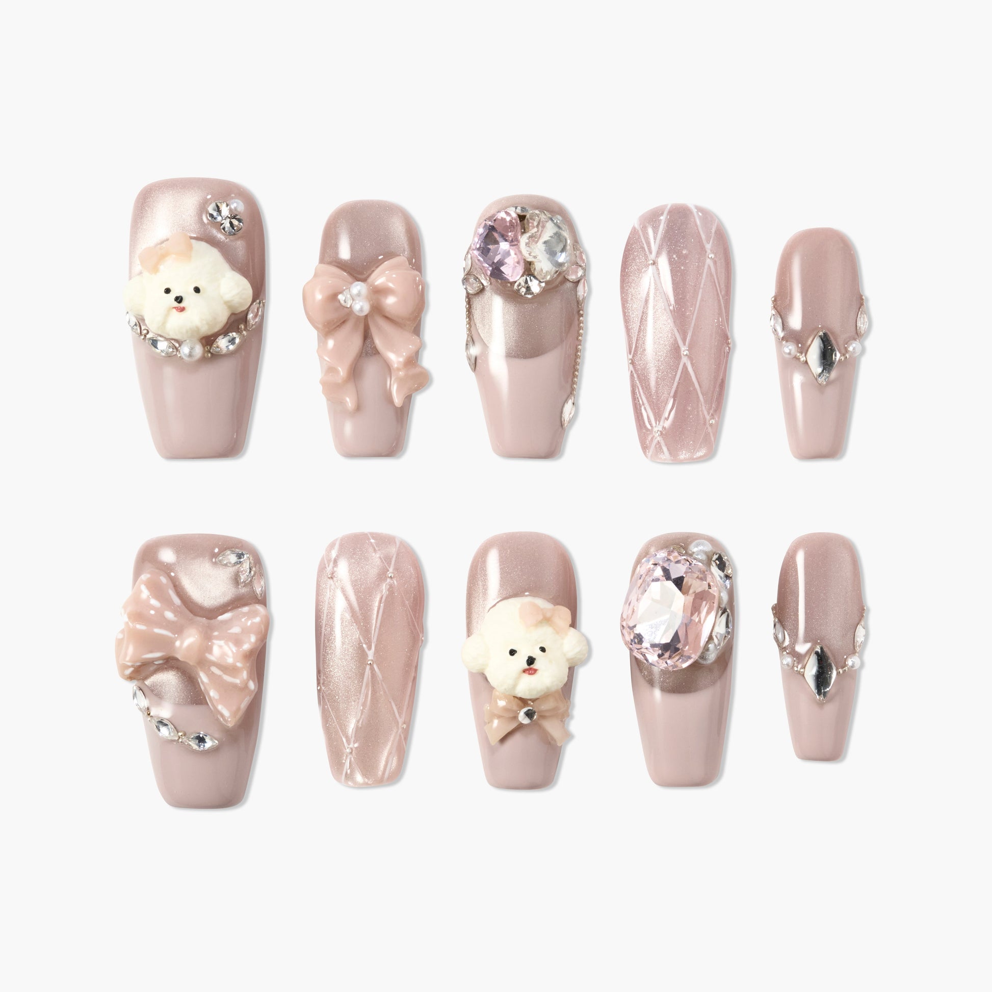 Handmade press-on nails with nude pink polish, 3D bows, bear charms, rhinestones, and quilted design