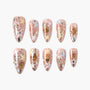 Handmade press-on nails with cat faces, pastel stars, and glitter on nude background