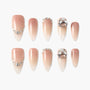 Nude ombre press-on nails with rhinestone and crystal accents, arranged on a white background.