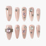 Nude pink press-on nails with rhinestones and gem accents in various shapes