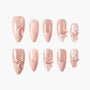Pink press-on nails with glitter, 3D bows, plaid, and floral designs, arranged on white background.