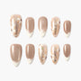 Handmade press-on nails with nude shimmer, French tips, and floral glitter accents
