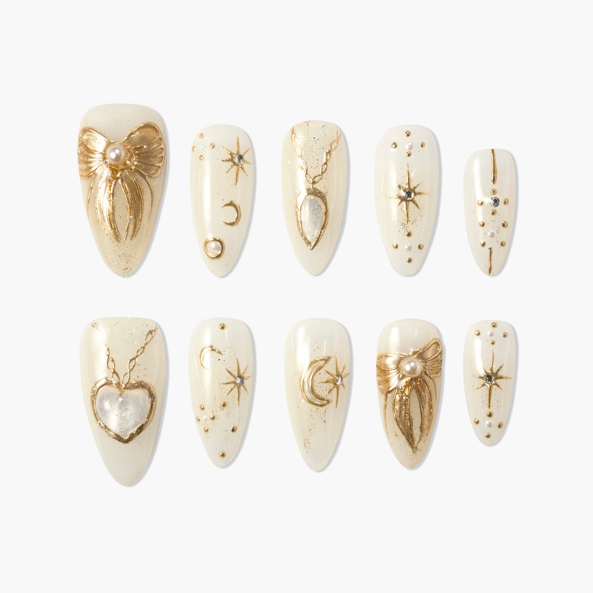 Cream press-on nails with gold celestial, heart, bow, and pearl charm designs