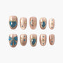 Handmade nude press-on nails with blue gems, gold celestial and bow designs, salon quality.