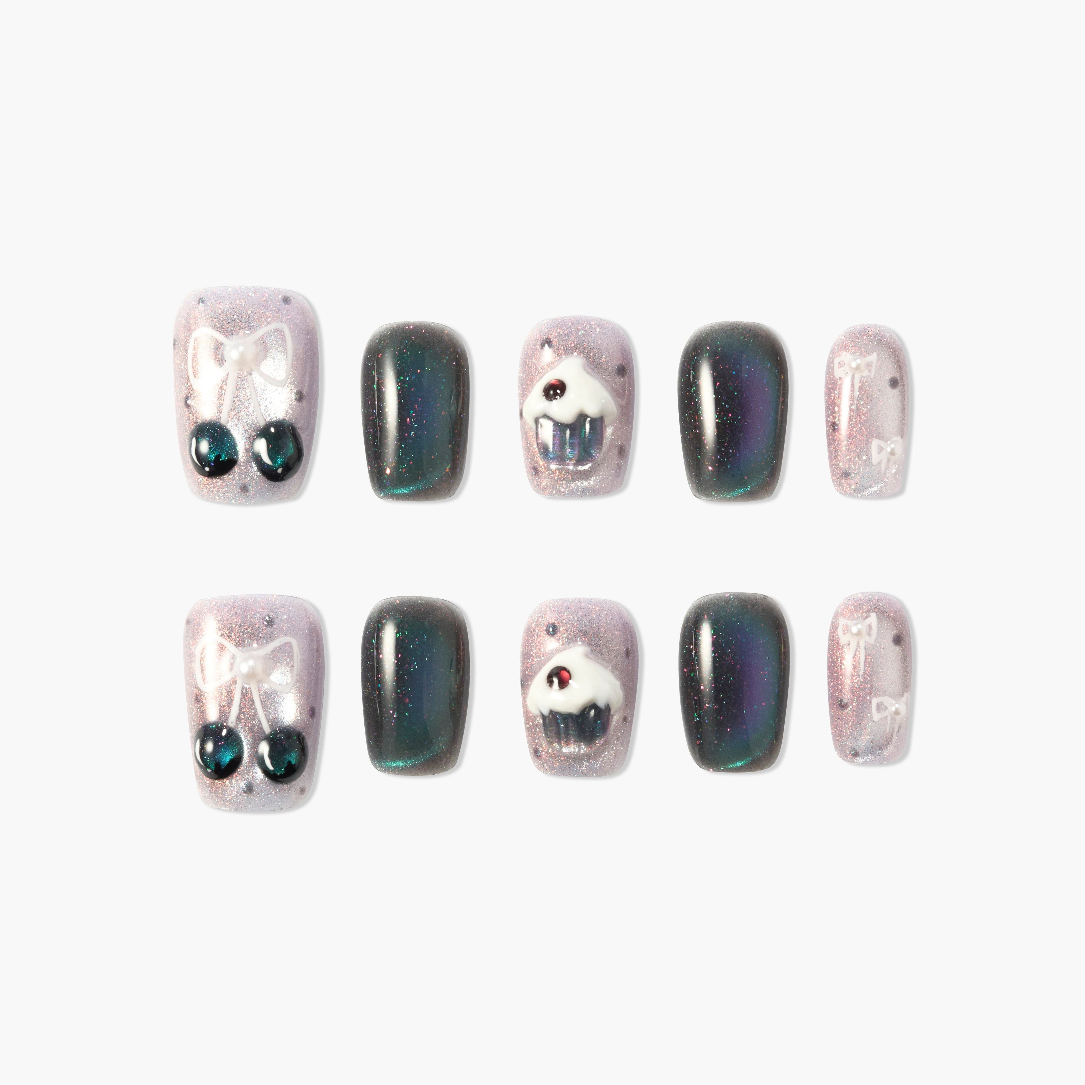Handmade press-on nails with sparkly pink and black designs, bows, cherries, and cupcake art.
