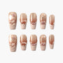 Nude pink press-on nails with pearl, bow, and rhinestone 3D accents on a white background