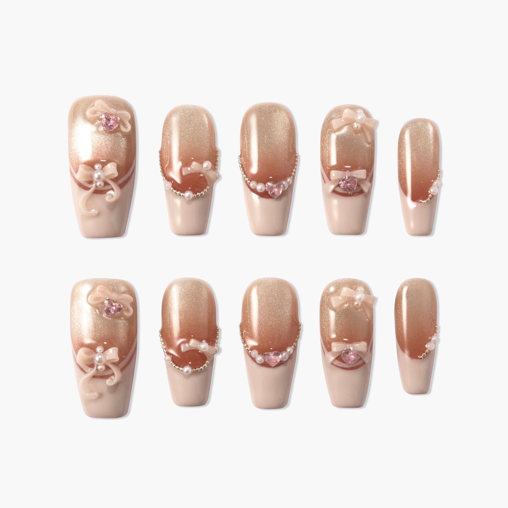 Nude pink press-on nails with pearl, bow, and rhinestone 3D accents on a white background